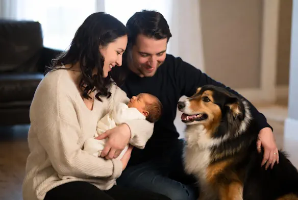 Parents présentant leur nouveau-né à leur chien dans un environnement calme et sécurisé.